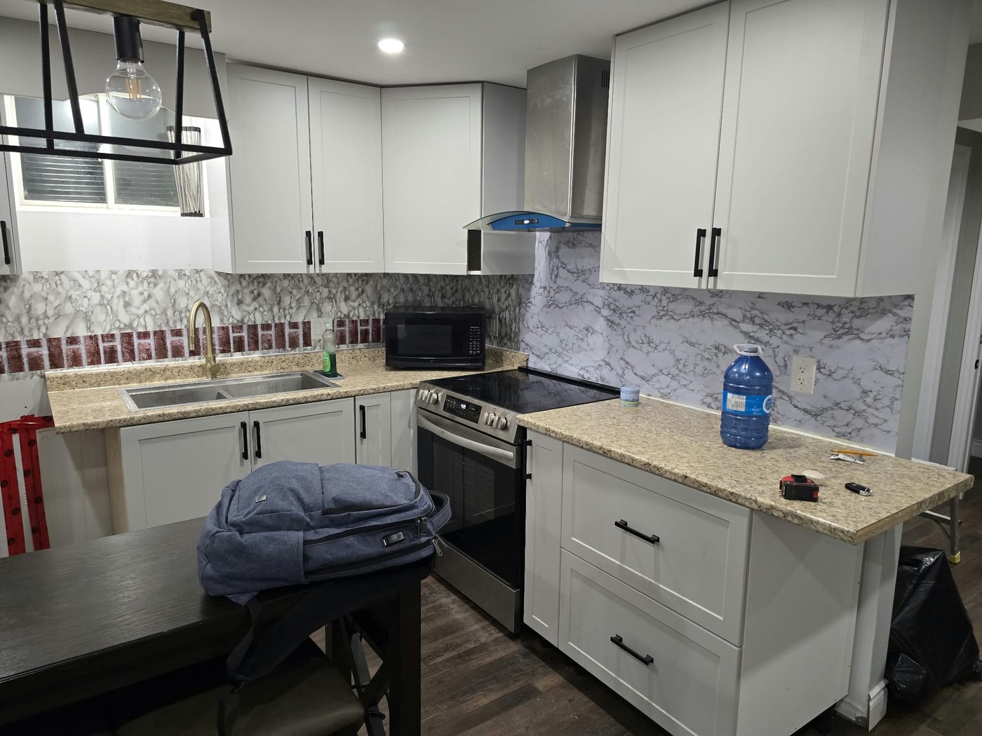 Finished basement kitchen with white cabinets and range hood