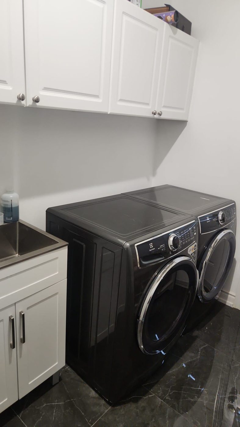 Renovated laundry room with new washer, dryer, sink and flooring